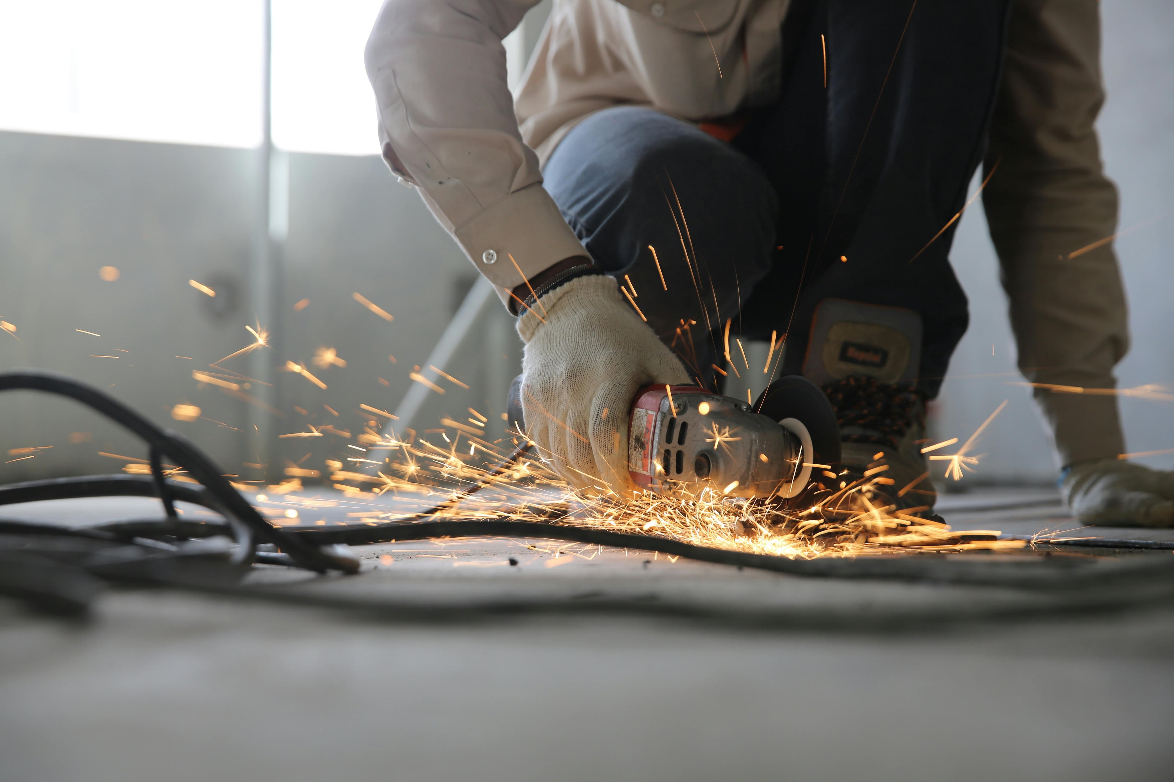Professionell isoleringsarbeten - A skilled industrial worker uses a grinder creating a burst of sparks indoors.